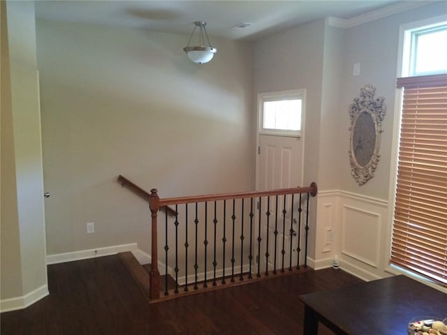 foyer with a wealth of natural light, dark wood-type flooring, and ornamental molding