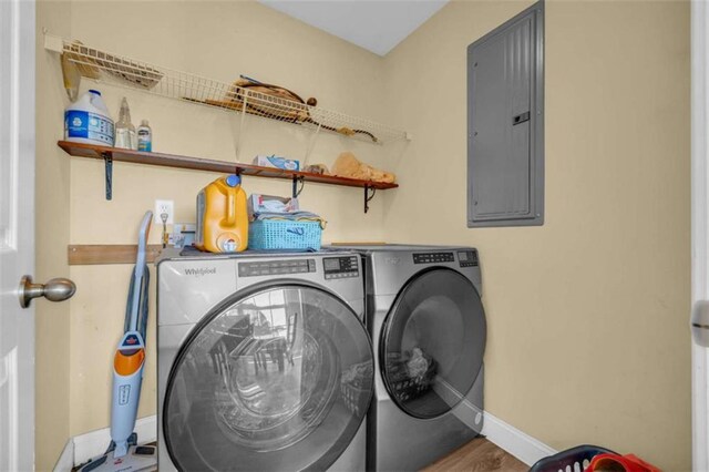 laundry room with hardwood / wood-style flooring, electric panel, and washer and dryer