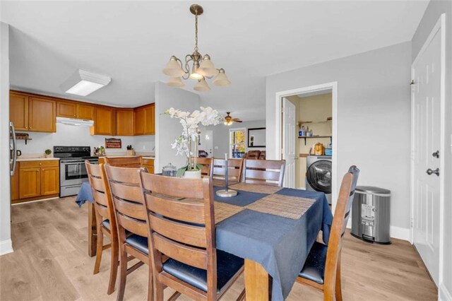 dining area featuring washer / clothes dryer, ceiling fan with notable chandelier, and light hardwood / wood-style flooring