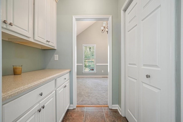 kitchen featuring white cabinetry, dark carpet, vaulted ceiling, and a notable chandelier