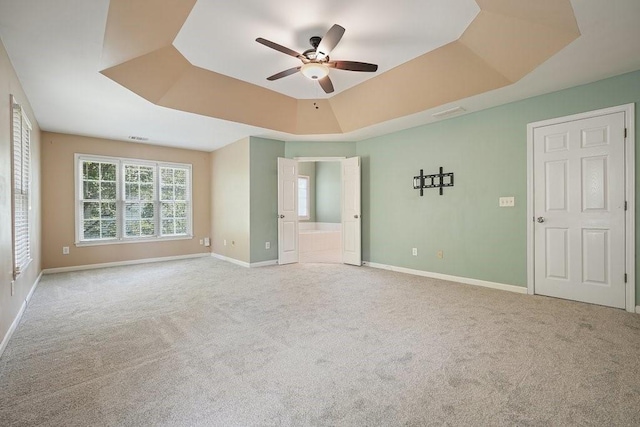 unfurnished bedroom with a tray ceiling, ceiling fan, and light colored carpet