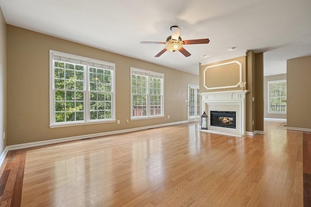 unfurnished living room with a wealth of natural light, ceiling fan, and light wood-type flooring