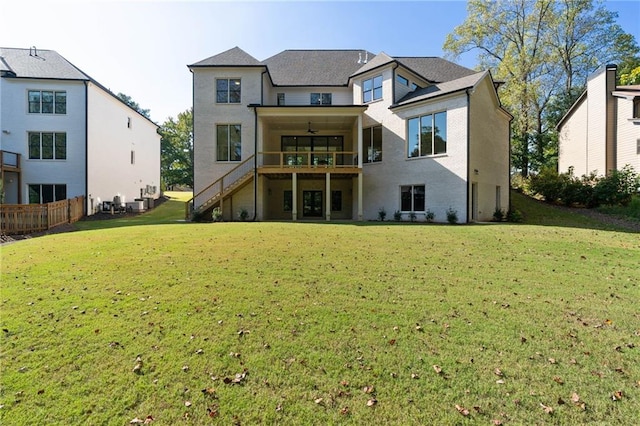 rear view of property with a balcony, a lawn, and ceiling fan