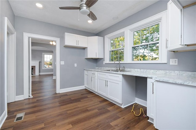 kitchen featuring white cabinetry, sink, dark hardwood / wood-style flooring, and light stone countertops