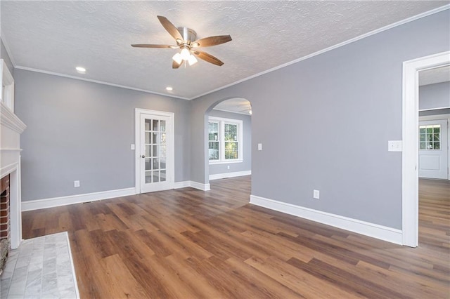 unfurnished living room with dark hardwood / wood-style flooring, a brick fireplace, a wealth of natural light, and ceiling fan