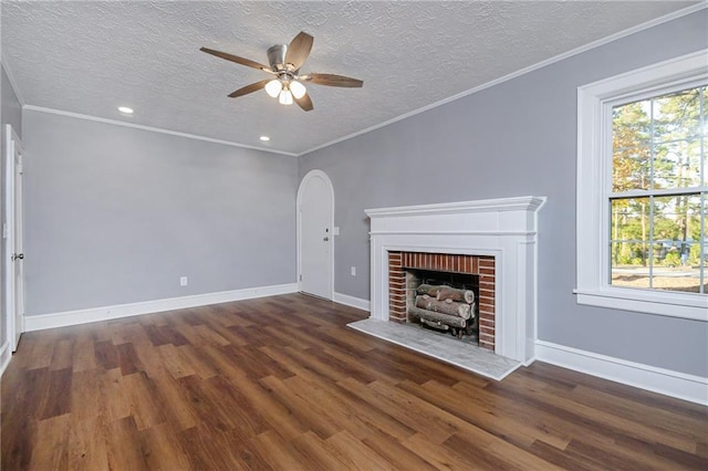 unfurnished living room featuring crown molding, a fireplace, dark hardwood / wood-style floors, and a healthy amount of sunlight