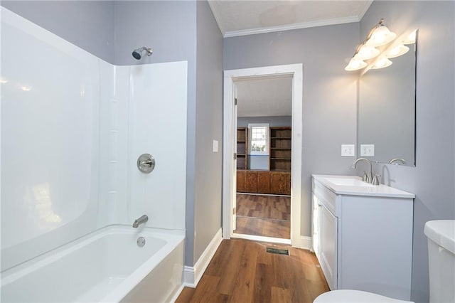 full bathroom featuring hardwood / wood-style floors, ornamental molding, vanity, toilet, and bathing tub / shower combination