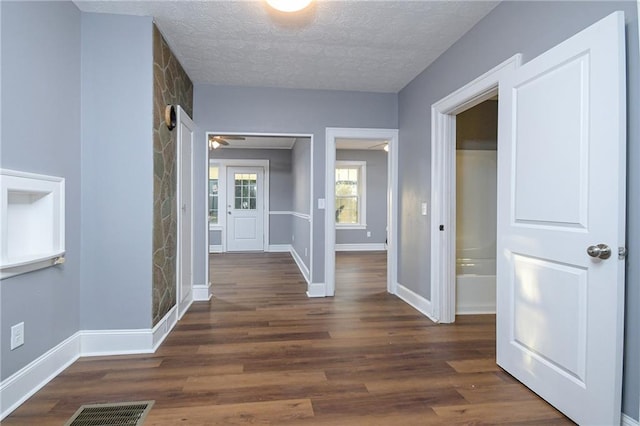 hall with dark hardwood / wood-style flooring and a textured ceiling