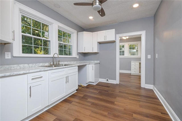 kitchen with sink, white cabinetry, light stone counters, dark hardwood / wood-style floors, and ceiling fan