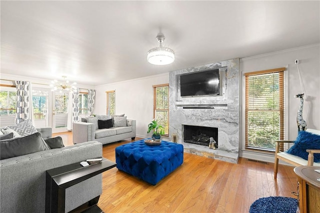 living room with ornamental molding, wood-type flooring, and a high end fireplace