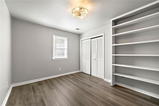 unfurnished bedroom featuring dark hardwood / wood-style flooring and a closet