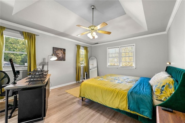 bedroom featuring a raised ceiling, ornamental molding, ceiling fan, and light hardwood / wood-style flooring