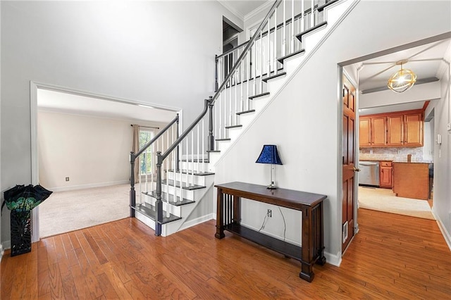 staircase with crown molding, a high ceiling, and hardwood / wood-style flooring