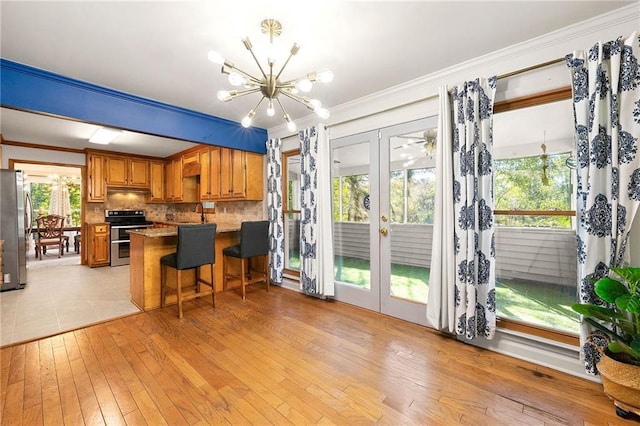 kitchen with appliances with stainless steel finishes, an inviting chandelier, a kitchen breakfast bar, kitchen peninsula, and french doors