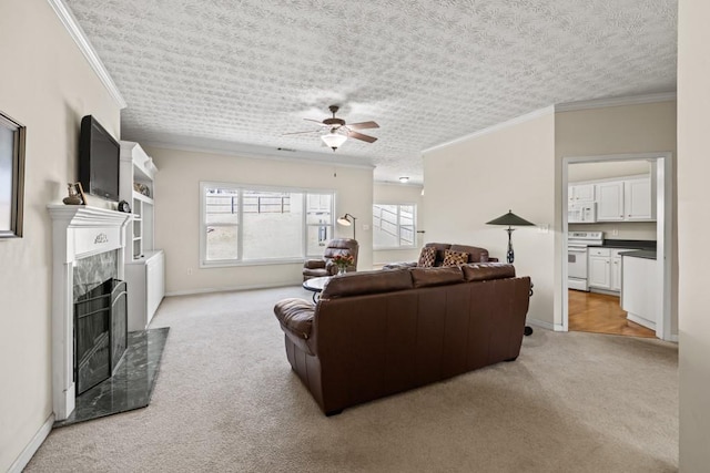 living room featuring light carpet, a ceiling fan, ornamental molding, a textured ceiling, and a fireplace