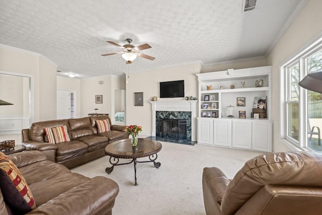 carpeted living room with crown molding, a premium fireplace, visible vents, and a textured ceiling