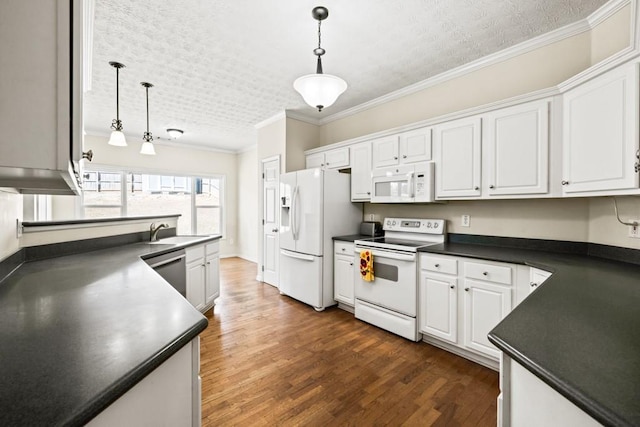 kitchen with white appliances, dark countertops, a sink, and crown molding