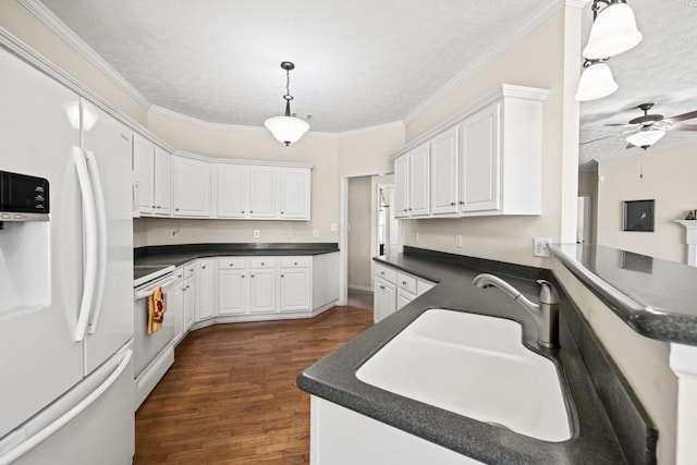 kitchen with white appliances, dark countertops, ornamental molding, white cabinetry, and a sink