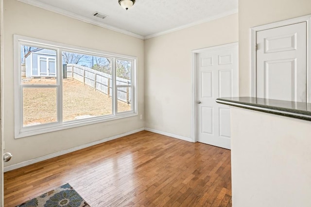 unfurnished dining area featuring ornamental molding, visible vents, baseboards, and hardwood / wood-style flooring