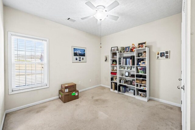 miscellaneous room featuring carpet floors, baseboards, a ceiling fan, and a textured ceiling