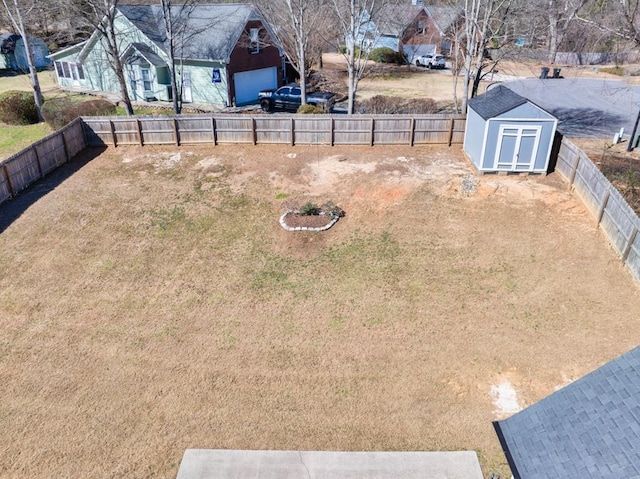 view of yard with an outbuilding, a fenced backyard, and a shed