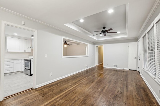 unfurnished living room featuring wood-type flooring, ornamental molding, a raised ceiling, and ceiling fan