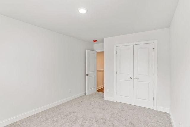 unfurnished bedroom with light carpet and a closet