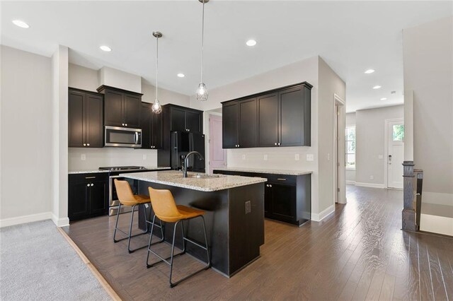 1954 Summit Trace Cir NW, Atlanta, GA 30318 - kitchen featuring appliances with stainless steel finishes, a breakfast bar area, a kitchen island with sink, dark wood-style flooring, and pendant lighting