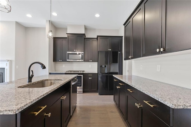 1954 Summit Trace Cir NW, Atlanta, GA 30318 - kitchen featuring stainless steel appliances, an island with sink, light wood finished floors, hanging light fixtures, and light stone countertops