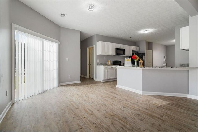 unfurnished living room with hardwood / wood-style floors, ceiling fan, and a textured ceiling