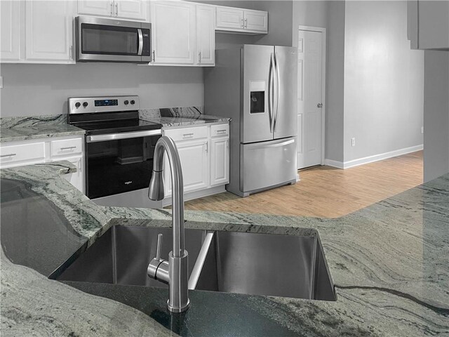 kitchen featuring white cabinets, hardwood / wood-style flooring, light stone counters, and sink