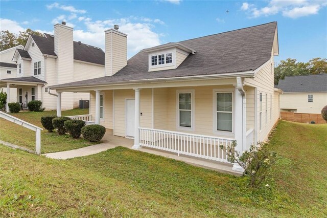 view of front facade featuring covered porch, cooling unit, and a front yard