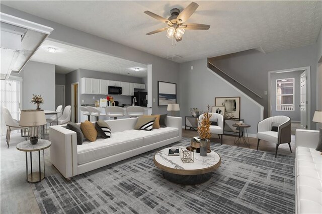 living room with ceiling fan, wood-type flooring, and a textured ceiling