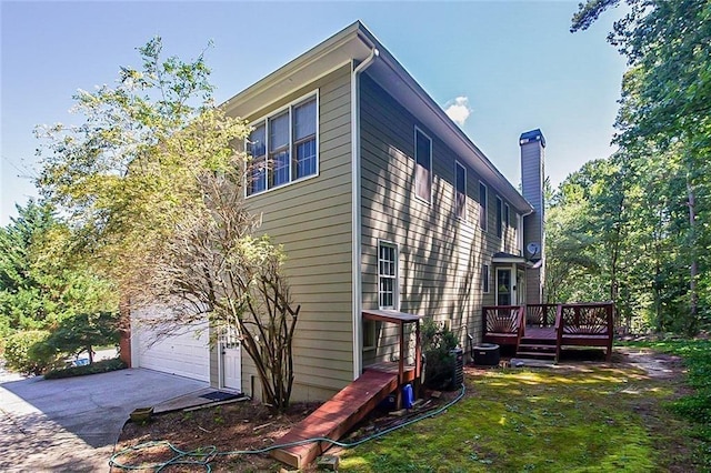 view of property exterior featuring a deck, driveway, a chimney, and an attached garage