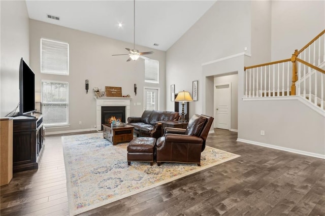 7927 Keepsake Ln, Flowery Branch, GA 30542 - living room featuring high vaulted ceiling, wood finished floors, stairway, a ceiling fan, and a warm lit fireplace
