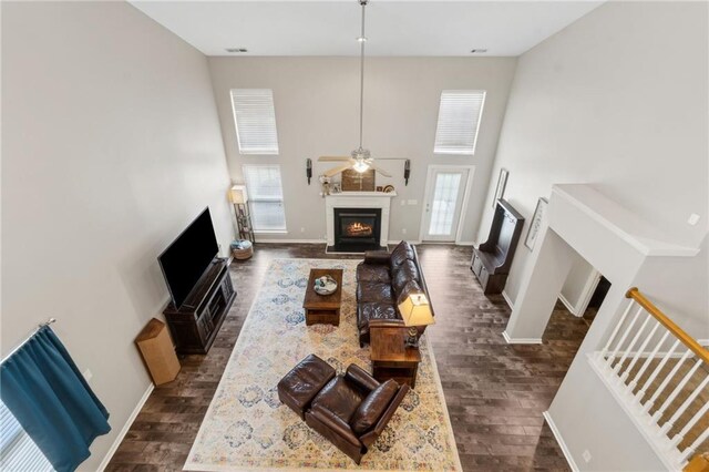 7927 Keepsake Ln, Flowery Branch, GA 30542 - living room featuring a lit fireplace, dark wood-type flooring, plenty of natural light, and a towering ceiling