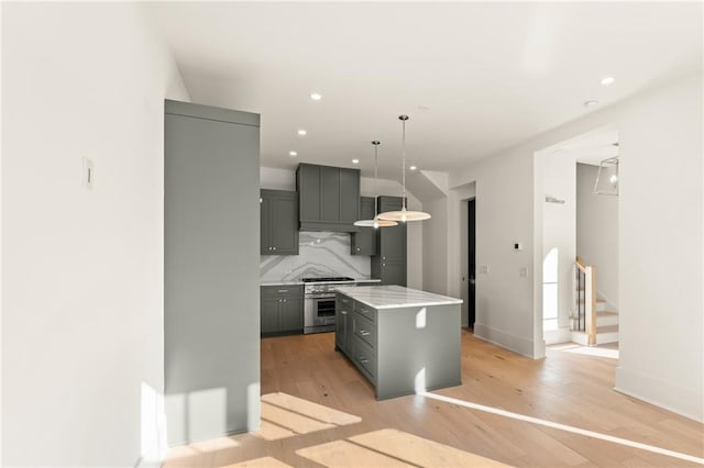 kitchen featuring gray cabinetry, pendant lighting, a center island, light hardwood / wood-style flooring, and decorative backsplash