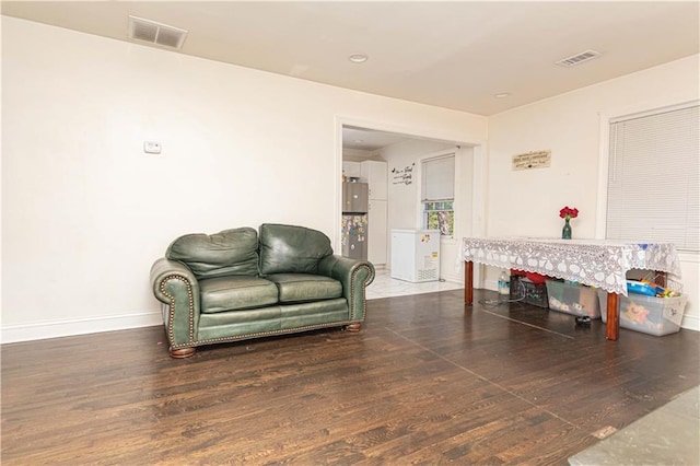 living area featuring visible vents, baseboards, and wood finished floors