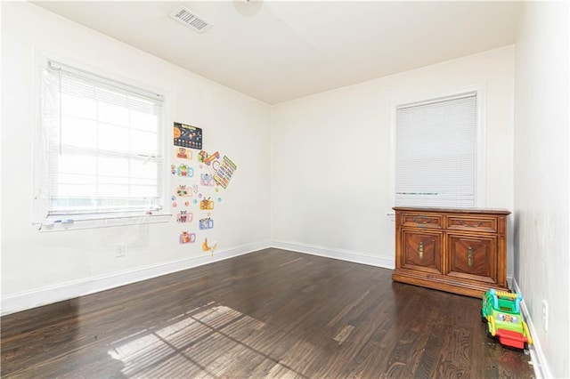 spare room with baseboards, visible vents, and dark wood-style floors