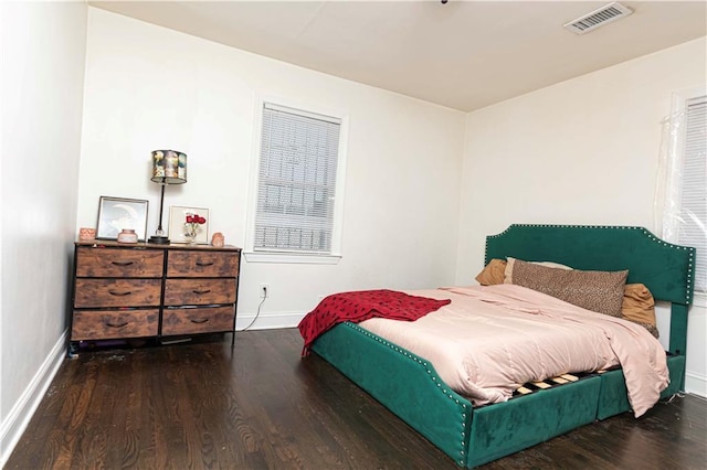 bedroom featuring baseboards, wood finished floors, and visible vents