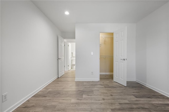 unfurnished bedroom featuring a spacious closet, light hardwood / wood-style floors, and a closet