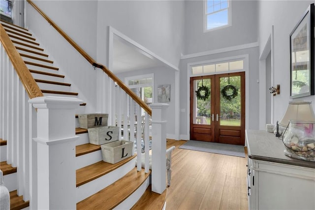 entrance foyer featuring a healthy amount of sunlight, light wood finished floors, stairs, and a towering ceiling