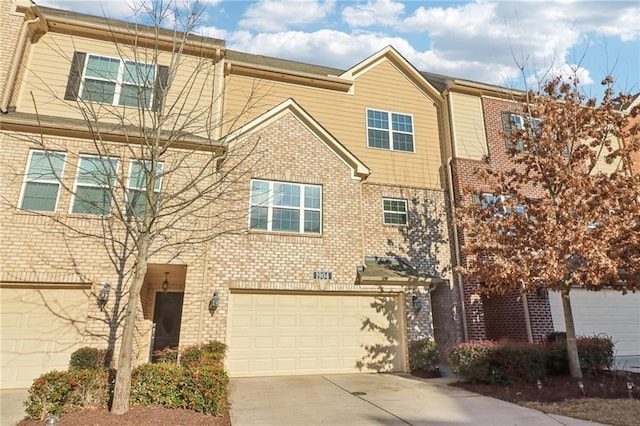 townhome / multi-family property with a garage, concrete driveway, and brick siding