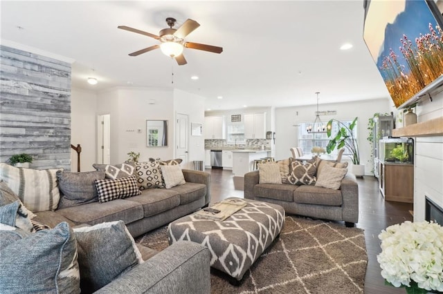 living area featuring recessed lighting, ceiling fan with notable chandelier, dark wood finished floors, and a glass covered fireplace