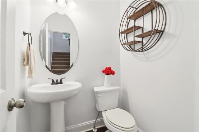 half bath featuring baseboards, a sink, and toilet