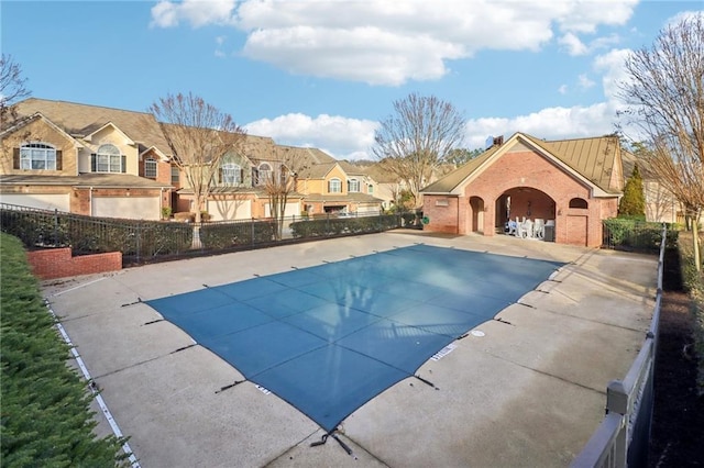 community pool with a patio, fence, and a residential view