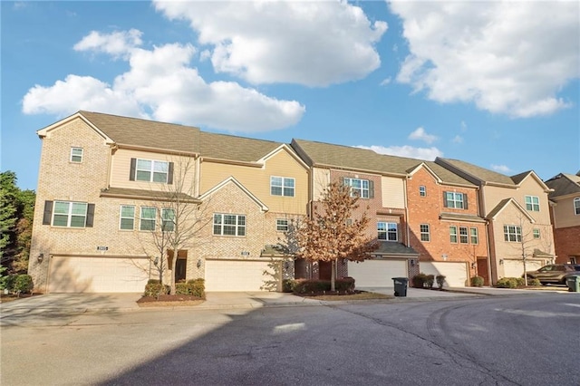 townhome / multi-family property with driveway, a garage, a residential view, and brick siding