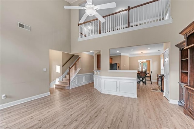 971 Reap Ln, Lawrenceville, GA 30043 - unfurnished living room featuring a towering ceiling, ornamental molding, light wood finished floors, a ceiling fan, and a chandelier