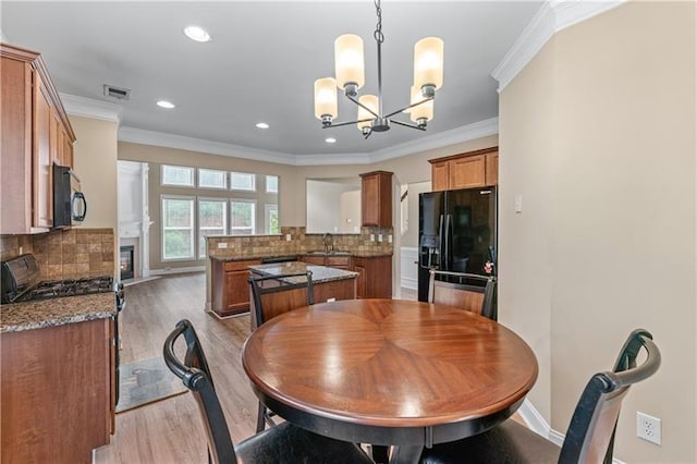 971 Reap Ln, Lawrenceville, GA 30043 - dining room featuring a chandelier, light wood-type flooring, crown molding, recessed lighting, and a glass covered fireplace
