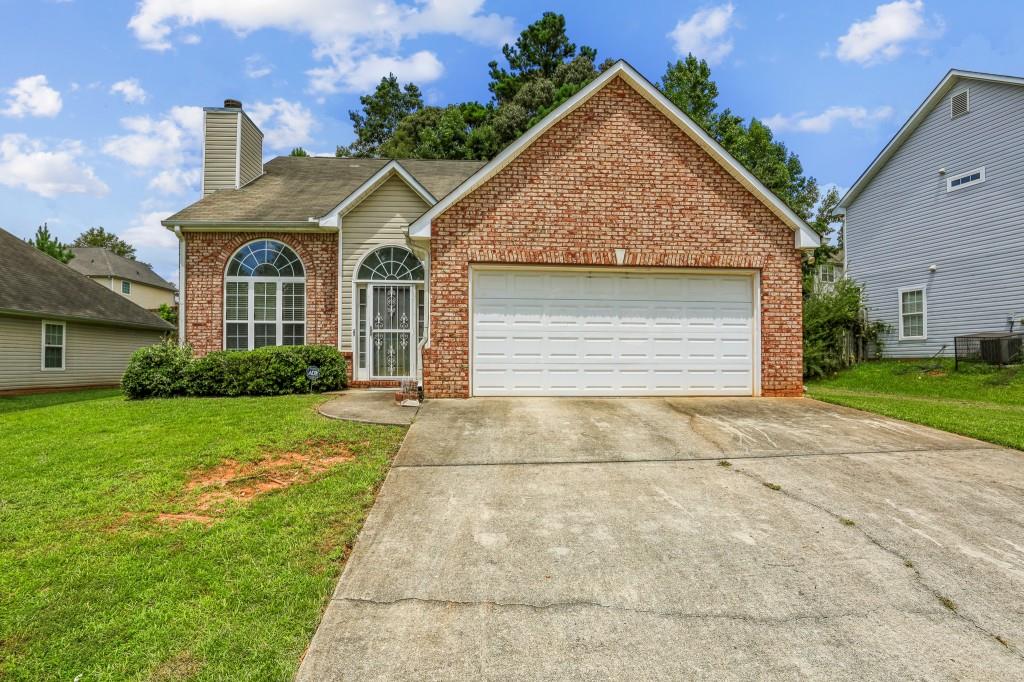 view of front property with a garage, cooling unit, and a front lawn